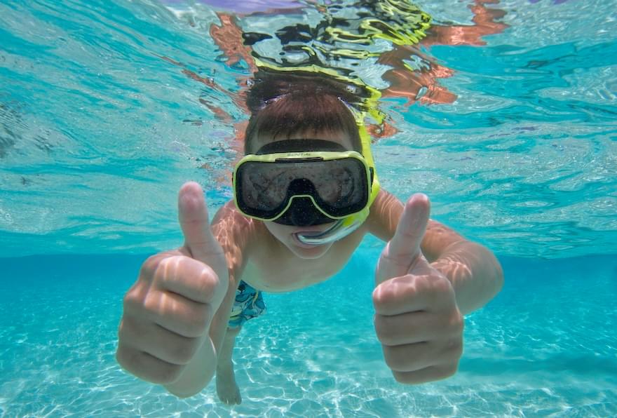 Snorkeler is giving a thumbs-up while exploring coral reefs, part of Cayman Island's tourist attractions