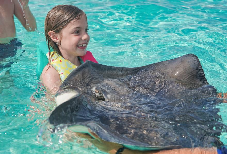 Child holding a stingray safely, showcasing the interactive fun of Cayman stingray city tours