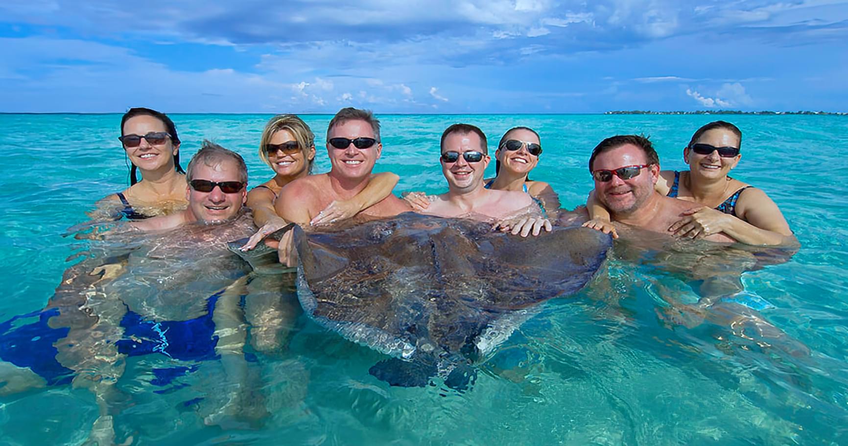 Friends posing with a stingray on a tour, capturing the moment
