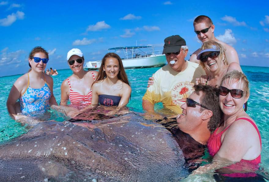 Group gathered around a stingray during one of the best stingray city tours in the Cayman Islands, enjoying expert guidance