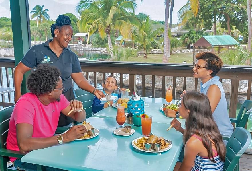 Guests dining at Schooners Bar & Grill, enjoying scenic views near the lagoon and turtle exhibits.