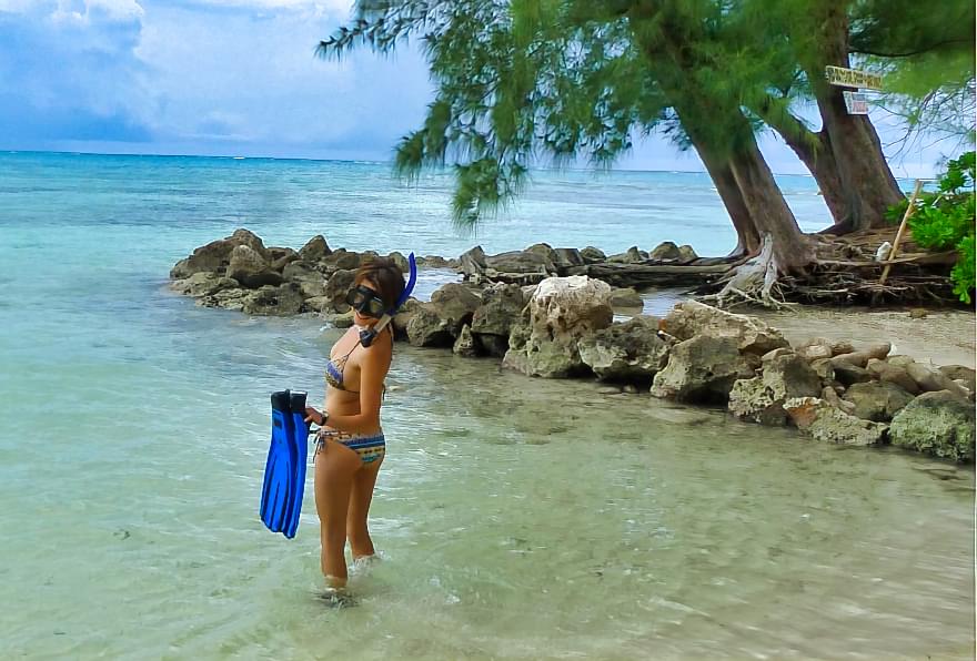 Visitor snorkeling in calm waters near Rum Point Beach, exploring marine life