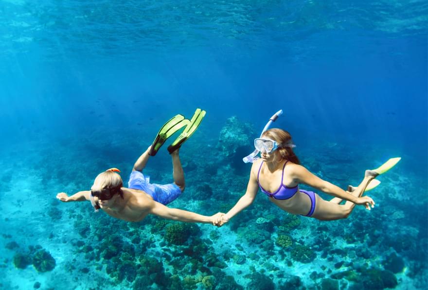 Two snorkelers exploring coral reef demonstrating snorkeling safety in tropical waters