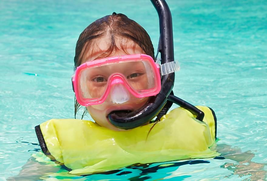 Young snorkeler with a snorkel safety vest enjoying a safe underwater adventure