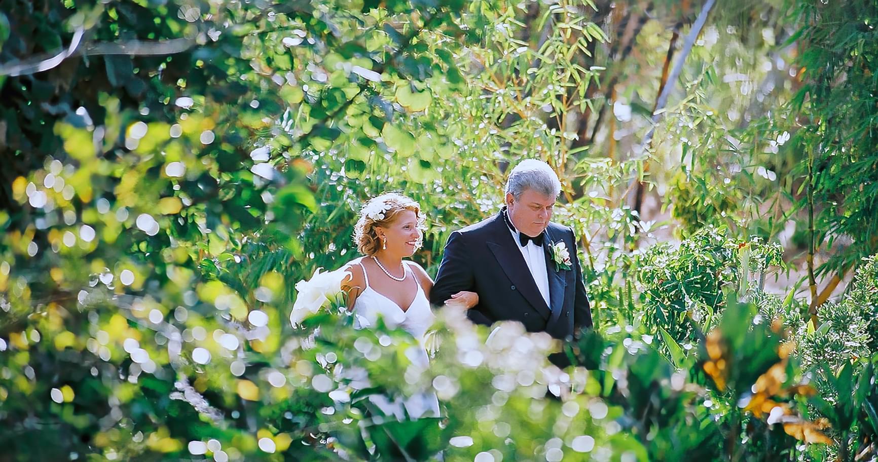 Bride and father walking through lush gardens at Pedro St. James for a charming ceremony