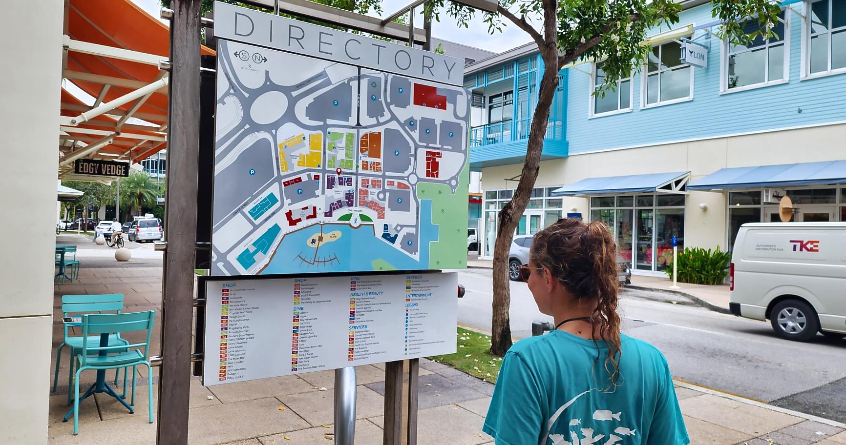 Visitor explores market sign in Camana Bay, highlighting local attractions