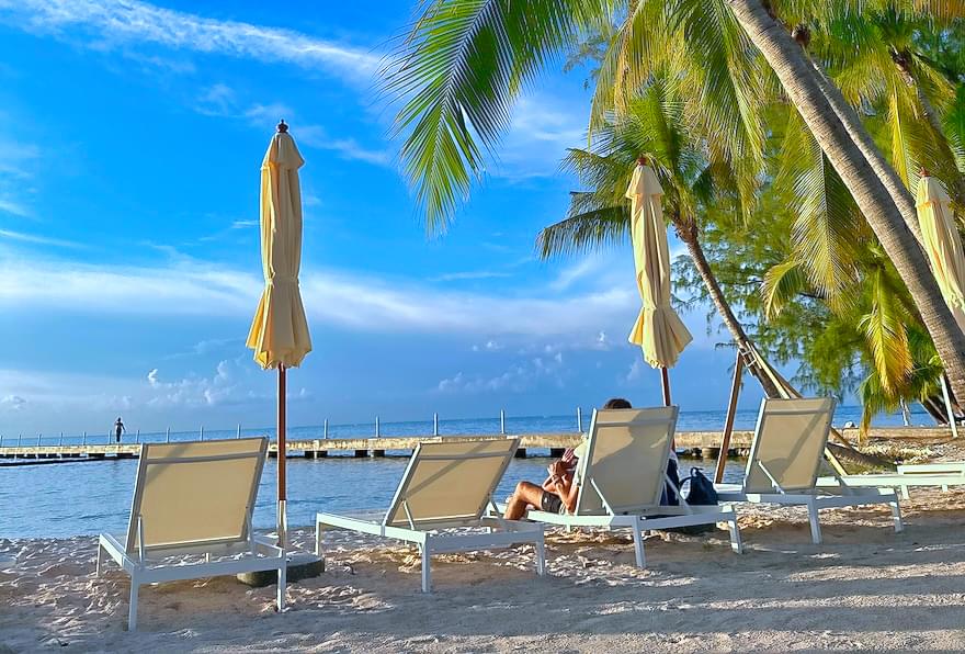 Relaxing beach chairs under palm trees at Rum Point, a perfect Cayman Islands attraction