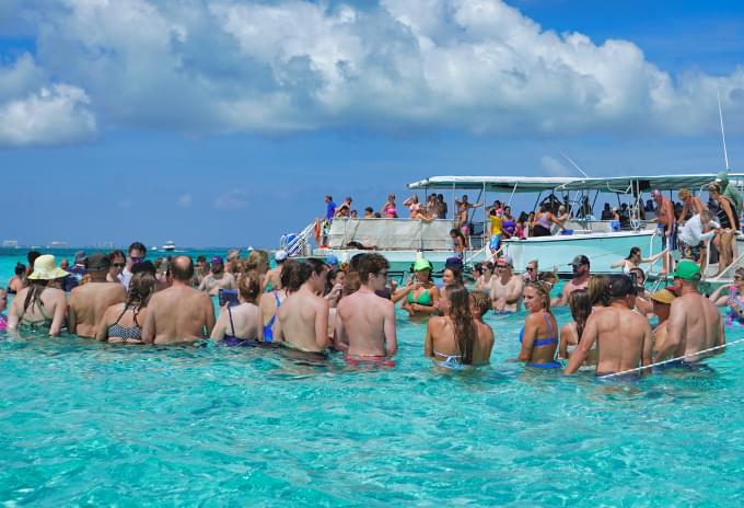 Crowd interacting with stingrays at Stingray City, a must-visit attraction with boat rental Cayman