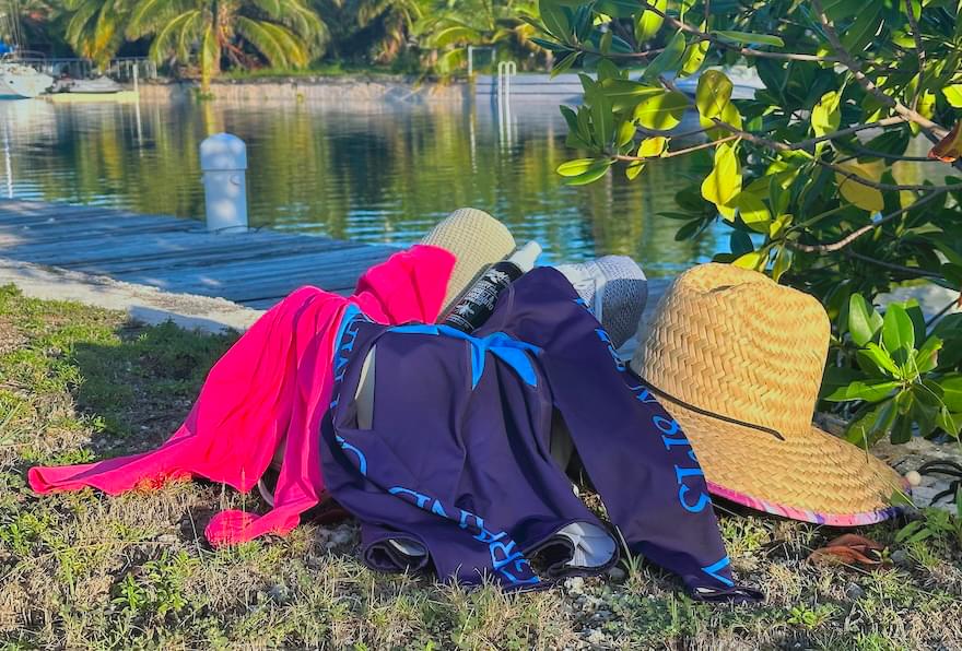 clothing and beach accessories placed beside calm waterfront in tropical setting
