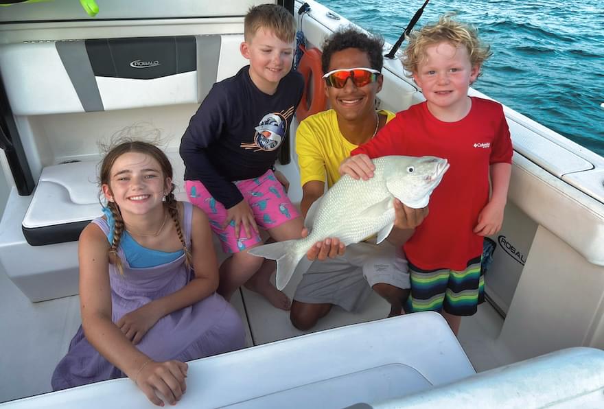happy kids posing with fish caught on family boat trip